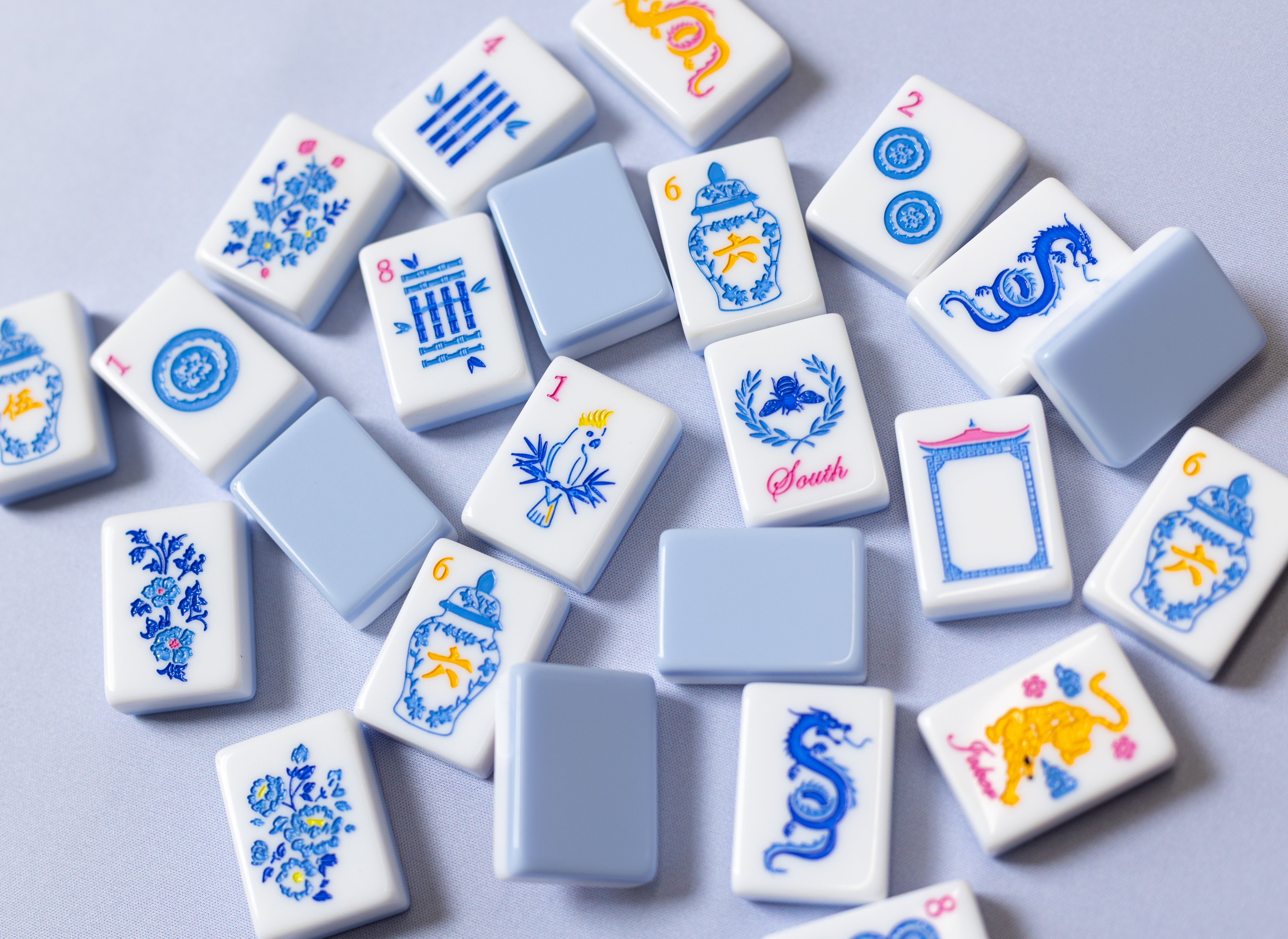 Mahjong tiles with blue and orange ginger jars on a blue mat
